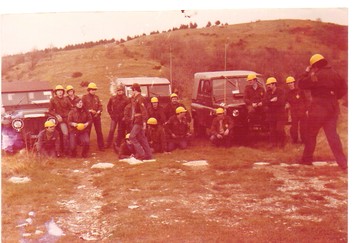 Foto vecchia di uomini in tuta verde e casco giallo