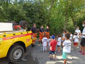 Gruppo di adulti Protezione Civile e bambini dietro un'auto gialla